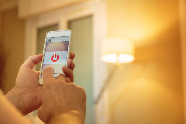 An adult uses a smartphone to adjust the light in a room. 