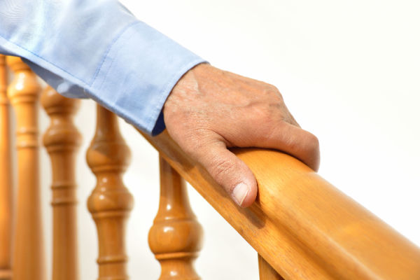 A man's hand holds onto the railing of a staircase. 