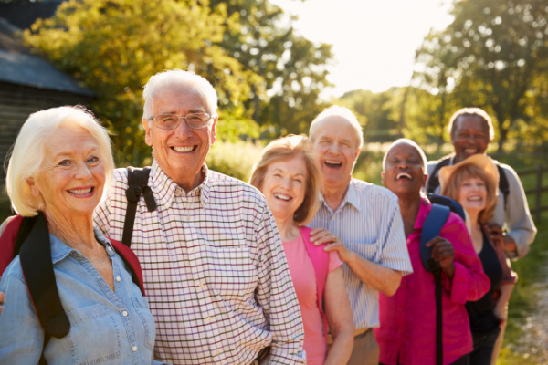 A group of seniors smiles at the camera before going on a hike or walk. 