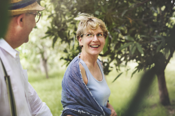 A senior woman smiles at a senior man next to her as they walk outside