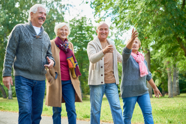 A group of seniors walk outside together. They are smiling and laughing.