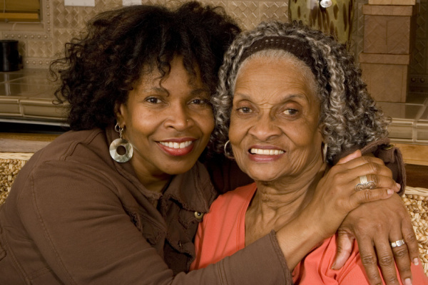 A daughter embraces her mother as they both smile.