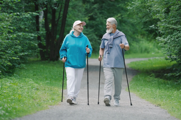 An elderly man and woman smile as they walk togther on a trail. 