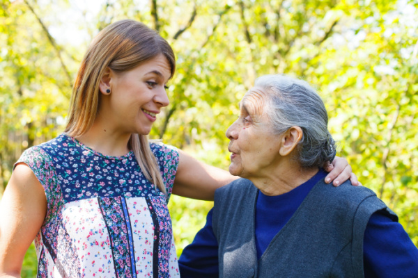 A younger woman and an elderly woman make eye contact as they speak to each other. 