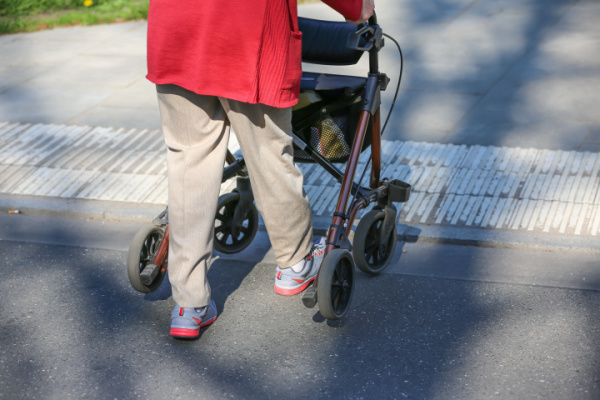 A senior uses a walker outside. 