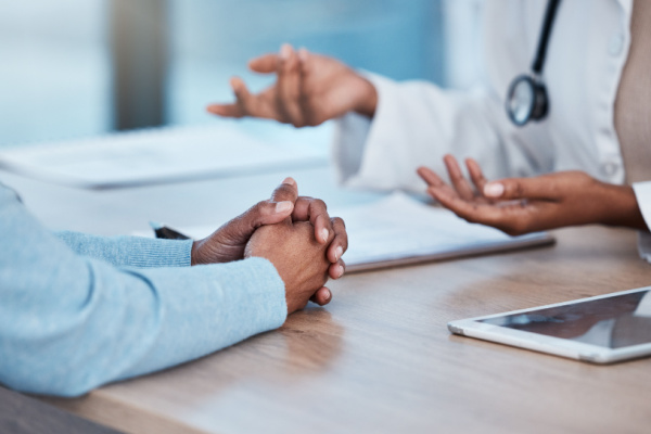 A doctor and patient chat while sitting across a desk from each other. 