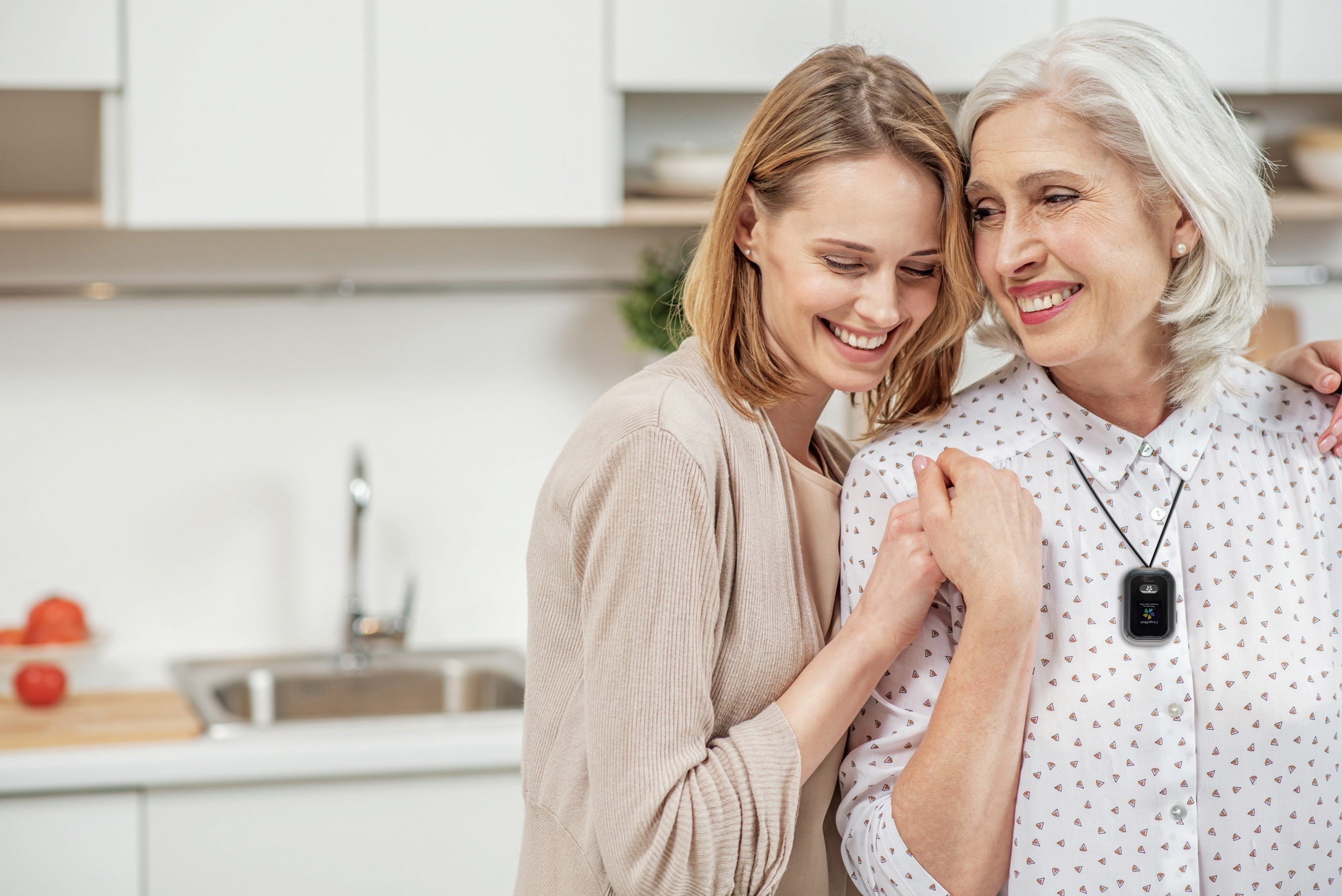 A senior woman and younger woman look at each other and smile as they stand in the kitchen.