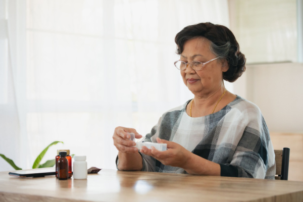 A senior woman opens up a vitamin or supplement organizer. 