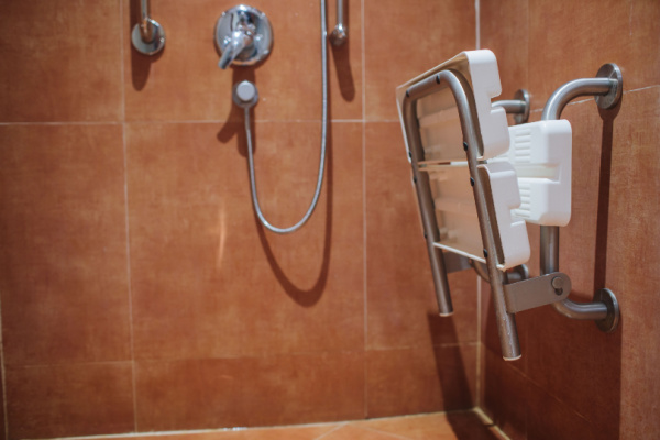 A shower with a safety shower chair attached to the side. 