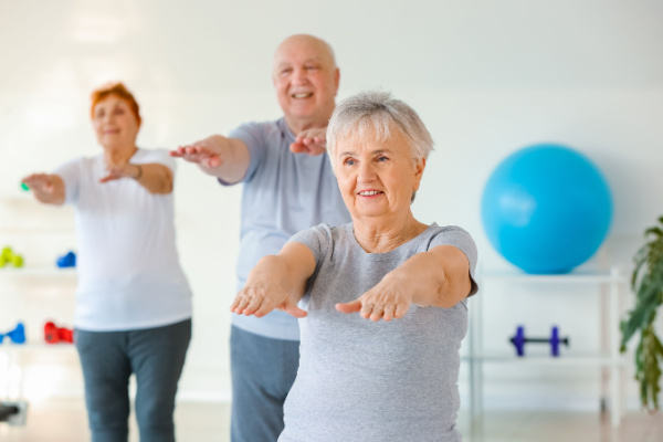 Three seniors hold their arms out as they exercise together.