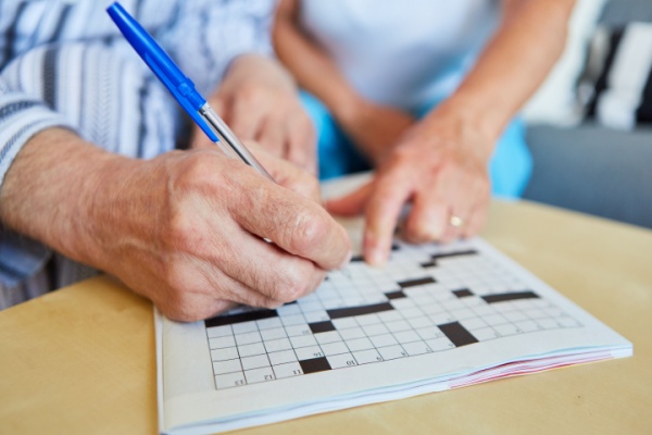 Two adults work on a crossword puzzle together.