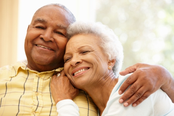 A smiling senior man and woman sit close to each other.