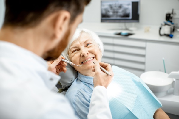 A senior woman smiles while in the dentist chair. 