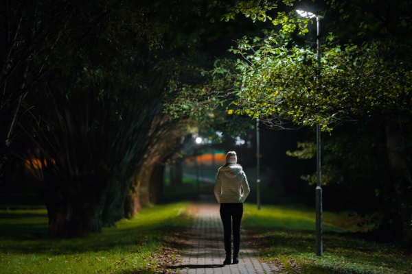 A woman walks along a dark path at night.