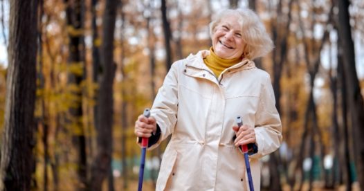 A smiling senior woman hikes outdoors.