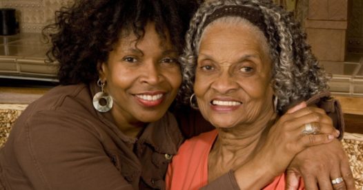 A daughter embraces her mother as they both smile.
