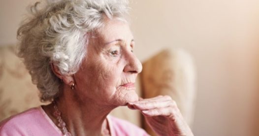 A senior woman looks pensive as she holds her hand to her chin.