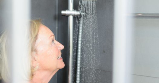 A senior woman smiles in the shower.