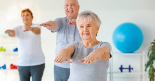 Three seniors hold their arms out as they exercise together.