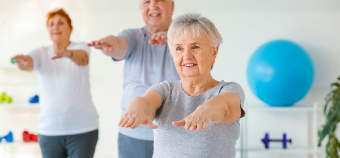Three seniors hold their arms out as they exercise together.